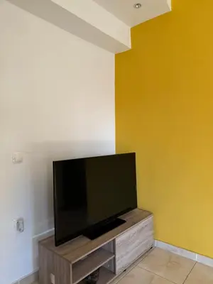 a flat screen tv sitting on top of a wooden entertainment center at Sunshine Bliss Apartment in Athens