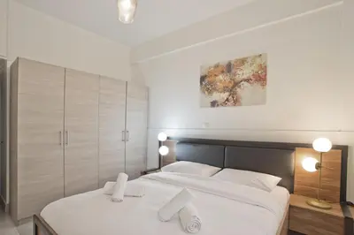 a bedroom with a large white bed with white pillows at Milena Comfy Piraeus Reno Apt AC & Full Kitchen in Piraeus