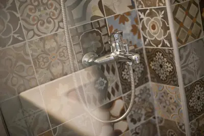 a shower nozzle in a bathroom with a tile wall at Milena Comfy Piraeus Reno Apt AC & Full Kitchen in Piraeus