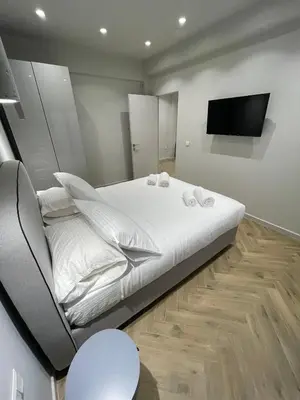 a bedroom with a large white bed and a flat screen tv at Down Town Nea Smyrni in Athens