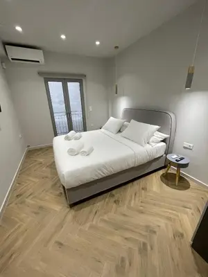 a bedroom with a large white bed with a wooden floor at Down Town Nea Smyrni in Athens