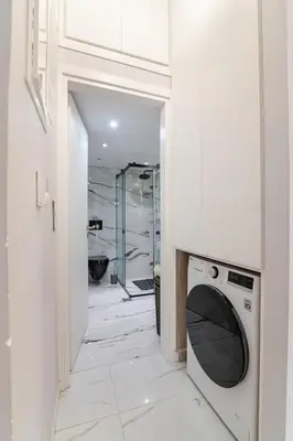 a bathroom with a washing machine in a white room at Warm and modern brand new apartment in Piraeus