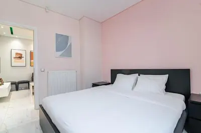 a white bedroom with a large white bed in it at Warm and modern brand new apartment in Piraeus