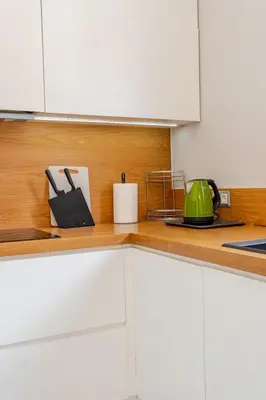 a kitchen with white cabinets and a wooden counter top at Warm and modern brand new apartment in Piraeus