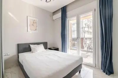 a bedroom with a bed and a large window at Warm and modern brand new apartment in Piraeus