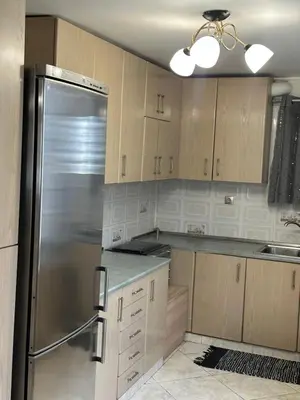 a kitchen with wooden cabinets and a stainless steel refrigerator at Peaceful Cottage Porto Rafti in Porto Rafti