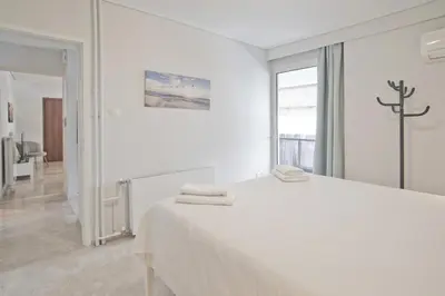 a white bedroom with a bed and a window at Belle Helene Luxury, Fully Reno, Athenian Riviera in Athens