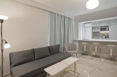 a living room with a couch and a kitchen at Belle Helene Luxury, Fully Reno, Athenian Riviera in Athens