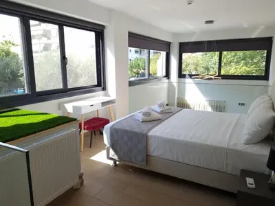a bedroom with a large bed with windows at 10 Apartments & Suites Athens in Athens