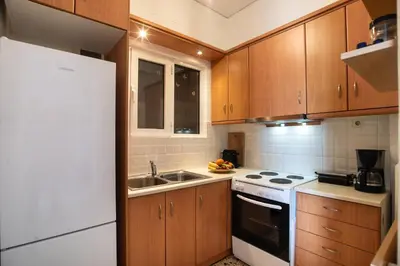a kitchen with wooden cabinets and a white refrigerator at Modern Apartment in Cholargos in Athens