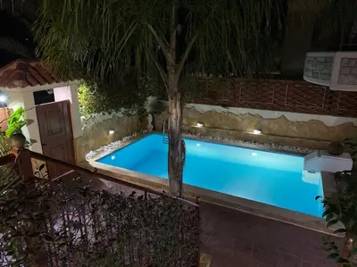 a pool at night with a palm tree and lights at Pool Garden House near the Sea in Vari