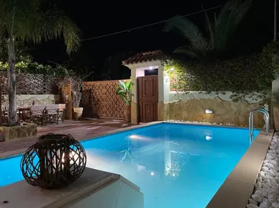 a swimming pool in a backyard at night at Pool Garden House near the Sea in Vari