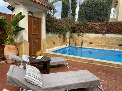 a swimming pool with chairs and a table next to it at Pool Garden House near the Sea in Vari