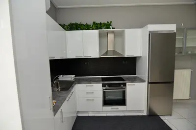 a kitchen with white cabinets and a stainless steel refrigerator at Athenian Riviera Beach front apartment 2 minutes from Tram stop in Athens