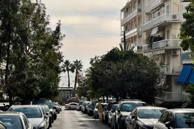 a street filled with cars parked next to a building at Athenian Riviera Beach front apartment 2 minutes from Tram stop in Athens