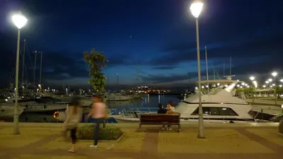 a group of people sitting on a bench at a marina at night at Athenian Riviera Beach front apartment 2 minutes from Tram stop in Athens