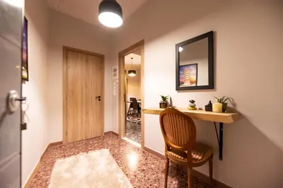 a hallway with a chair and a desk and a mirror at STAMOS Apartment airport in Spáta