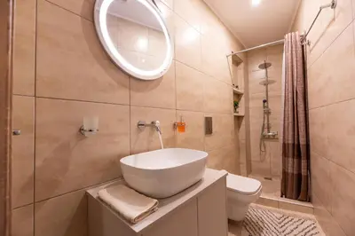 a bathroom with a sink and a toilet and a mirror at STAMOS Apartment airport in Spáta
