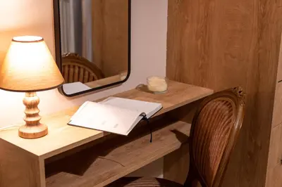 a desk with a lamp and a book and a mirror at STAMOS Apartment airport in Spáta