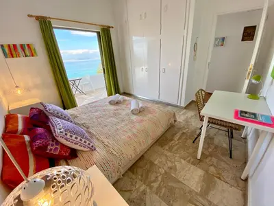 a bedroom with a bed and a table and a window at The Beachhouse Apartments in Vaia