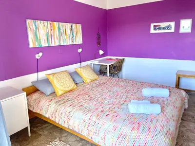 a bedroom with a bed with a purple wall at The Beachhouse Apartments in Vaia