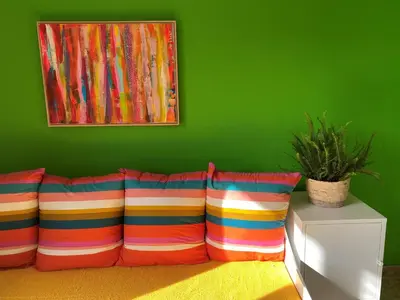 a couch with two colorful pillows and a green wall at The Beachhouse Apartments in Vaia