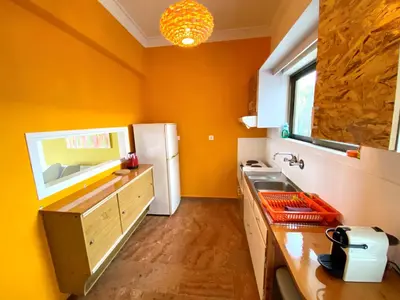 a kitchen with orange walls and a white refrigerator at The Beachhouse Apartments in Vaia