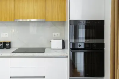 a kitchen with white cabinets and black appliances at Magnificent Riviera Residence VIPGreece in Athens