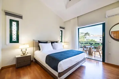 a bedroom with a large bed and a balcony at Vouliagmeni Athenian Riviera Villa in Athens