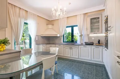 a kitchen with white cabinets and a chandelier at Vouliagmeni Athenian Riviera Villa in Athens