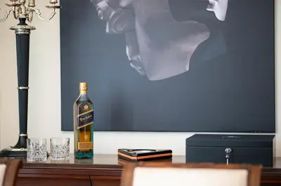 a bottle of whiskey sitting on a table with glasses at Vouliagmeni Athenian Riviera Villa in Athens