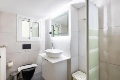 a white bathroom with a sink and a shower at Santorini 2-Bedroom Apartment in Nea Smyrni in Athens