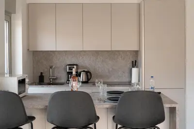 a kitchen with two chairs and a counter with white cabinets at Elegant and cozy flat near Pagrati region (D1) in Athens