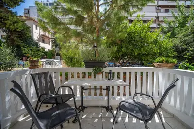 a table and chairs on a balcony with a tree at ANGEL , Luxury 2BD apartment next to the Beach in Athens