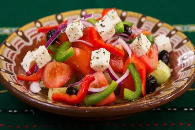 a bowl of salad with vegetables and cheese on a table at Stunning Athens Apartment 1 Bedroom Apartment Juvia Athinaidos in Athens