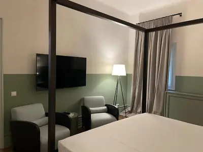 a bedroom with a bed and a tv and two chairs at Stunning Athens Apartment 1 Bedroom Apartment Juvia Athinaidos in Athens