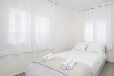 a white bedroom with a bed with towels on it at Zografou House Living by 8essentially in Athens