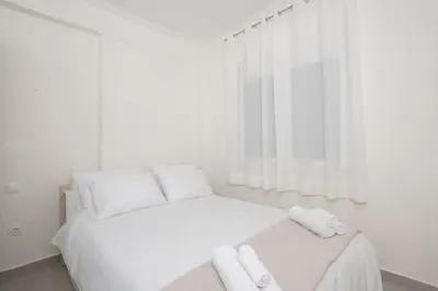 a white bedroom with a bed with towels on it at Zografou House Living by 8essentially in Athens