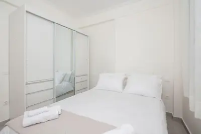 a white bedroom with a white bed and a mirror at Zografou House Living by 8essentially in Athens