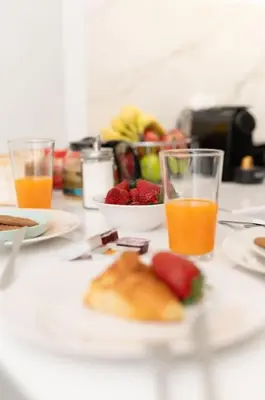 a table with plates of food and glasses of orange juice at Zografou House Living by 8essentially in Athens