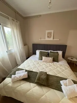 a bedroom with a large white bed with a window at Guest house Elina in Kalívia Thorikoú