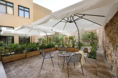 a patio with tables and chairs and umbrellas at Magnificent Athens Villa 1 Bedroom Villa Aizen Garden View in Athens