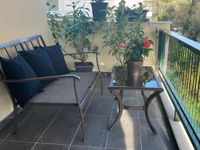 a balcony with a bench and a table and potted plants at glyfada luxury home in Athens