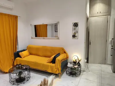 a living room with a yellow couch and two tables at The loft in Piraeus