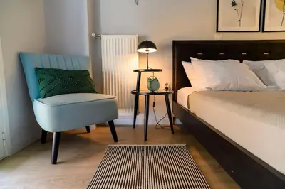 a bedroom with a bed and a chair and a lamp at Cosy Contemporary Luxury Urban Retreat in Athens in Athens