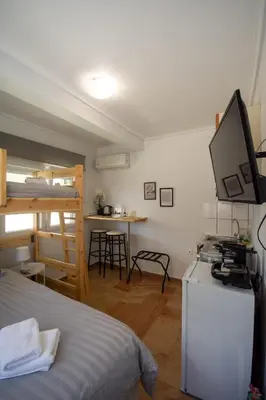 a bedroom with a bed and a desk with a television at Birdhouse Apartment Athens in Athens