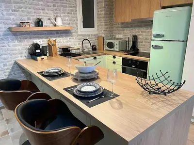 a kitchen with a counter with chairs and a green refrigerator at Hidden Garden of Kallithea in Athens