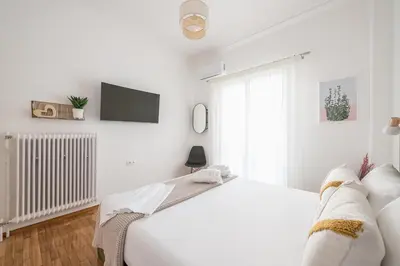 a white bedroom with a bed and a tv at The Business Suite by CloudKeys in Athens