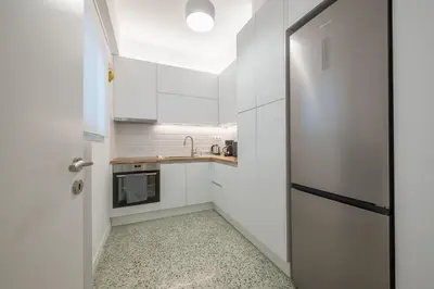 a small kitchen with white cabinets and a door at The Business Suite by CloudKeys in Athens