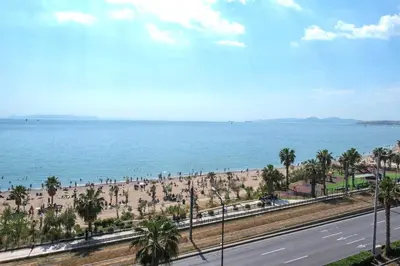 a view of a beach with palm trees and a road at Breathtaking seaview studio in Athenian Riviera in Athens